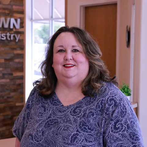 Carol, Scheduling Coordinator at Newtown Family Dentistry, smiling at the front desk